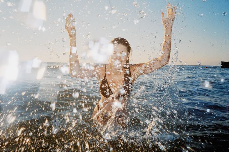 [A Woman In A Dark Swimsuit Is Standing In The Water With Arms Raised, Splashing Water Around](https://www.stills.com/images/a-woman-in-a-dark-swimsuit-is-standing-in-the-water-with-arms-raised-splashing-water-around/350960) by Steven Schultz
